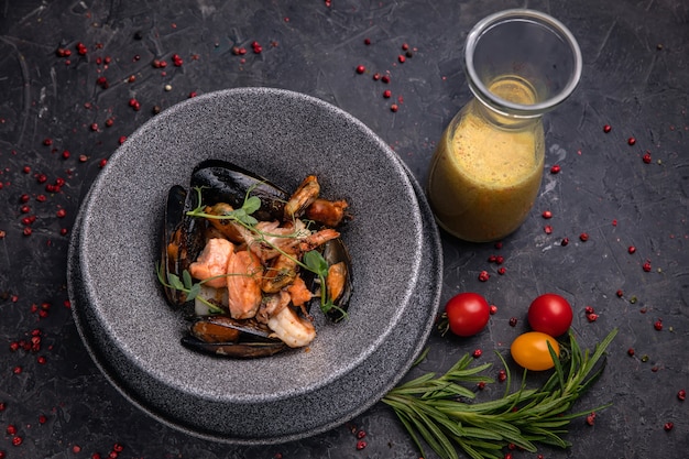 Фото Тайский суп с морепродуктами, креветками, лососем. подается на серой тарелке из глубокого камня на темном бетонном столе.