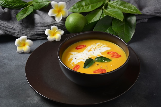 カフィアライムの葉、赤唐辛子、ガランガルルーツパウダーを使ったタイのスパイシーなカボチャとココナッツミルクのスープ。