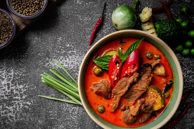 Thai spicy red curry with curry paste ingredients on rustic table - Thai food menu