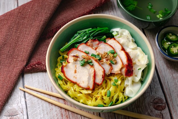 Photo thai street food - egg noodle with barbecued red pork and wonton  serving with soup