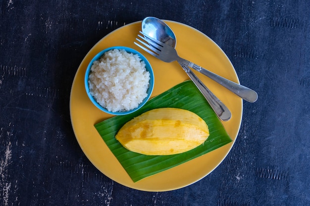 Десерт в тайском стиле, манго с липким рисом на тарелке