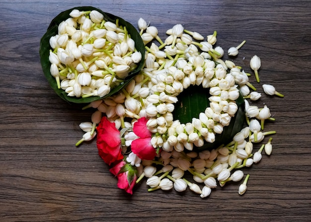 Thai style of jasmine garland and fresh jasmine flowers on\
wooden background