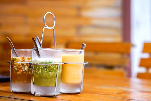 Thai style sauce in glass with glass base condiment holder on wooden table