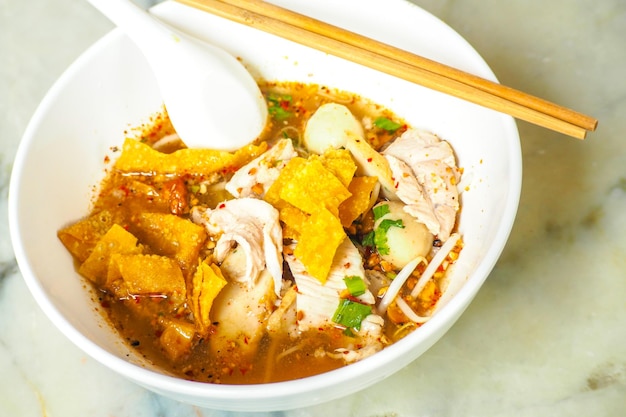 Thai Style Tom Yum Noodles with Minced Pork Spicy soup with wooden chopsticks in a white bowl on a w