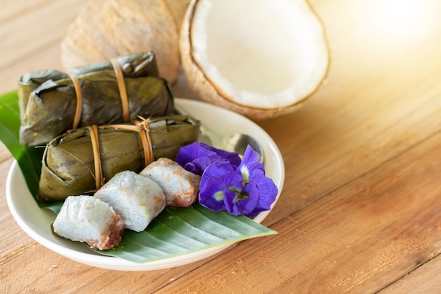 Photo thai traditional dessert sticky rice with bananas (khao tom mat) on wooden table