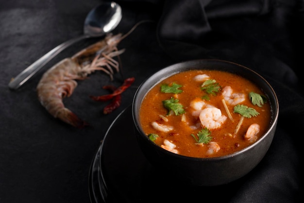 Thai tum yum soup in a black bowl