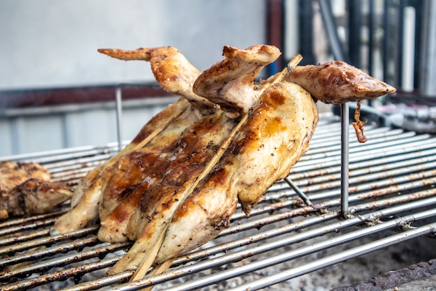 Pollo intero tailandese grigliato con carbone di legna sulla strada.