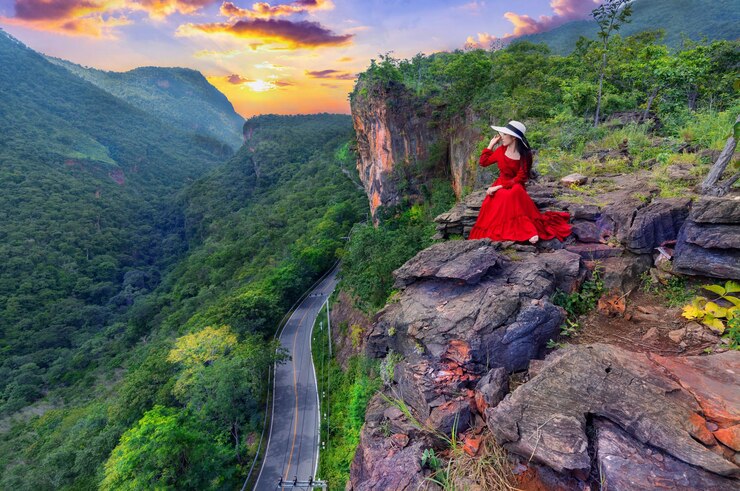 Photo thai woman in red dress sitting on the rock at pha luang daeng viewpoint chiang mai thailand
