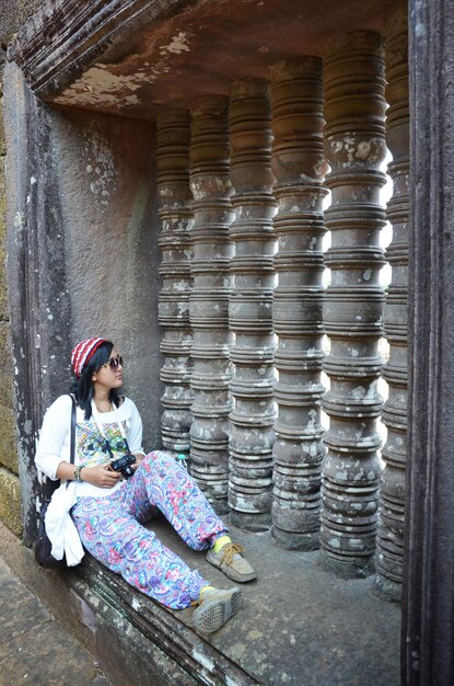 Тайская женщина сидит и фотографируется у окна Ват Пху или Ват Пху 10 век - это разрушенный кхмерский индуистский храм в Чампасаке, Лаос.