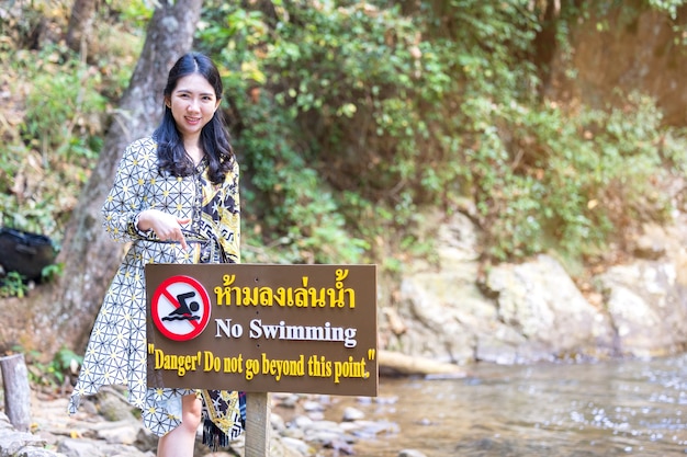 Тайские женщины указывают на знак запрета на плавание в этой области - противоречие