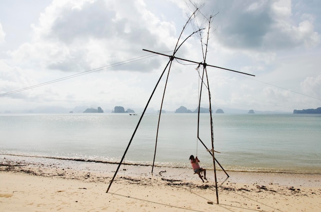 Thai women portrait and playing wooden bamboo swings hilltribe style on the beach at Ko Yao Noi in Phang Nga Thailand