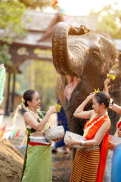 タイの若い女性は,タイの伝統的なドレスを着て,タイの新年日に水を散らす遊びをします.