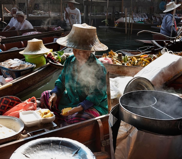 Foto thailandia, bangkok: 14 marzo 2007 - donna thailandese che prepara cibo al mercato galleggiante - editoriale