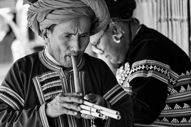 Foto thailandia, chiang mai, villaggio di tribù karen lungo collo hill (kayan lahwi), uomo karen in costumi tradizionali che suona un flauto
