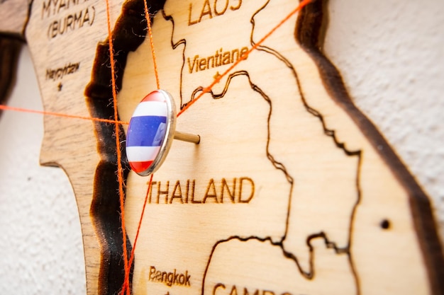 Photo thailand flag on the pin with red thread showed the paths on the wooden map