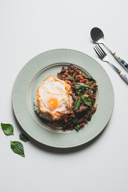 Thailand food stirfried beef and basil with fried egg on green\
plate thai food conceptthai street food