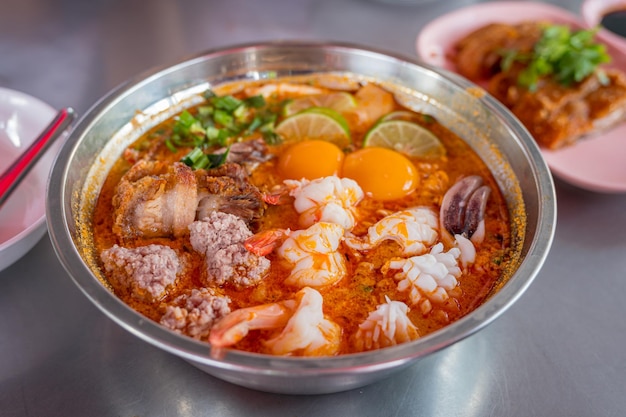 Foto thailandia food tumyum noodle con carne di maiale croccante e frutti di mare al mercato di strada della thailandia