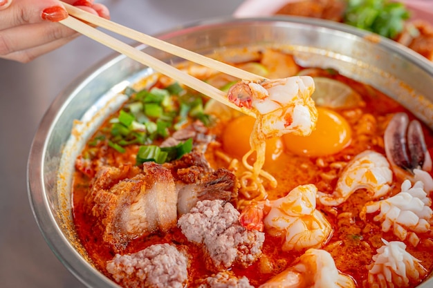 Thailandia food tumyum noodle con carne di maiale croccante e frutti di mare al mercato di strada della thailandia