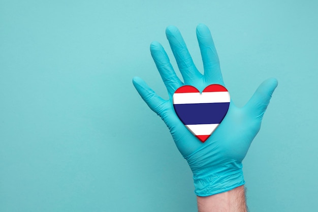 Photo thailand medical health heart nurse hand holding country heart flag