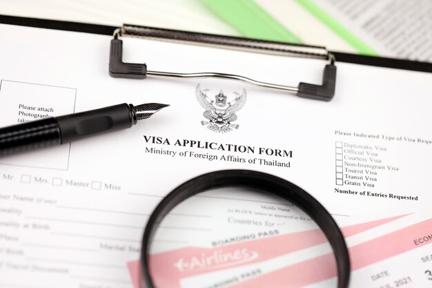 Thailand visa application form on a tablet lies on office table with pen and magnifying glass