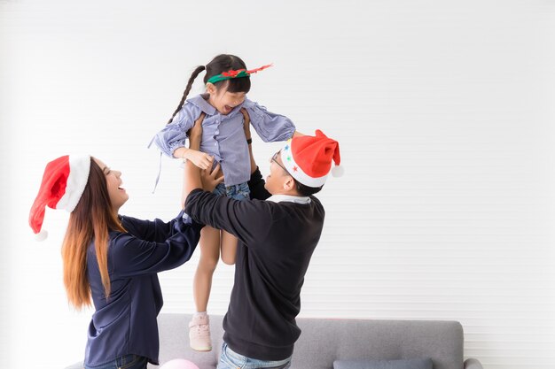 Thais-aziatische ouders dragen hun dochters liefdevol in de woonkamer. ze lachten en genoten van de vakantie.