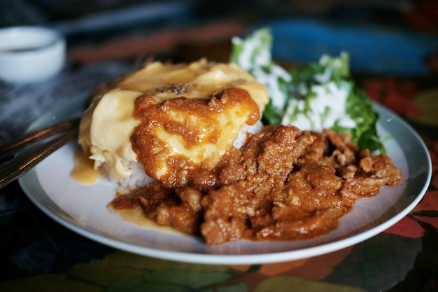 Thais eten Panaeng-curry met varkensvlees en omelet op gekookte rijst