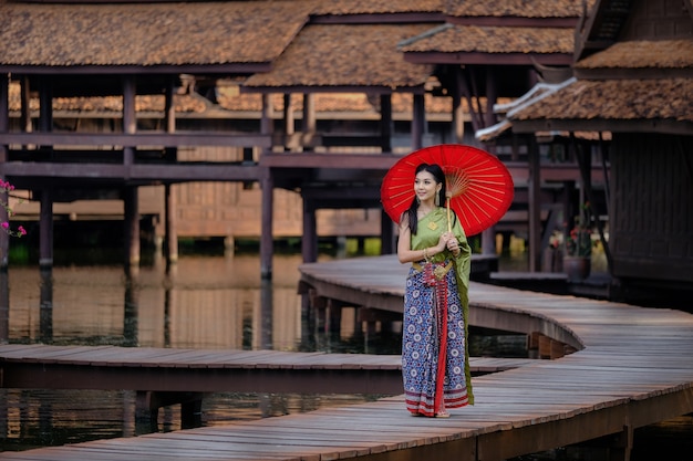Foto thais meisje in de rode paraplu van het traditionele kledingskostuum