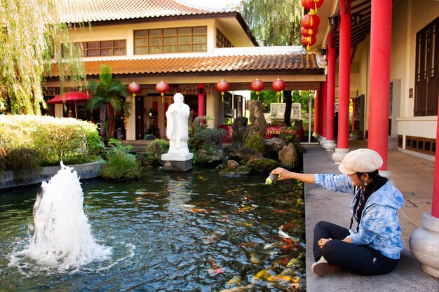 Thais vrouwenreisbezoek en het voeren van voedsel aan mooie karpers in de vijver van de Chinese tuin in het ThaiChinese Cultural Center op 19 december 2017 in Udon Thani, Thailand