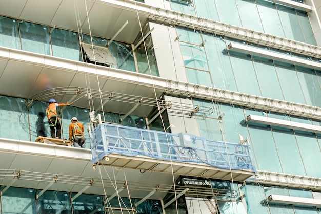 Thaise arbeiders zijn bezig met het stallen en schoonmaken van spiegels van gebouwen