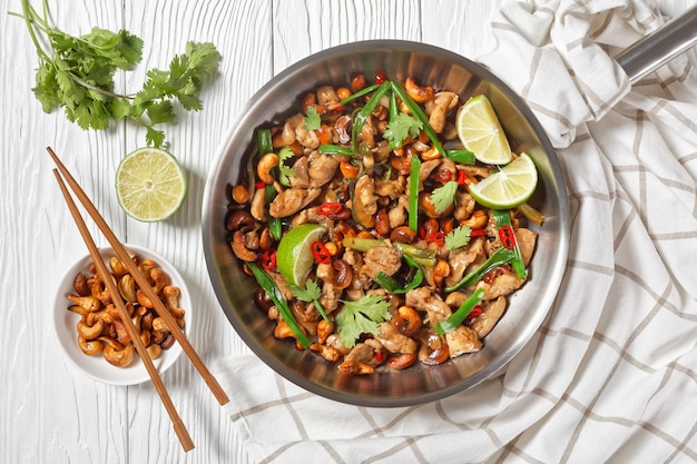 Thaise cashew-kip roerbak in een pan op een houten tafel met eetstokjes en ingrediënten horizontale weergave van boven plat lag