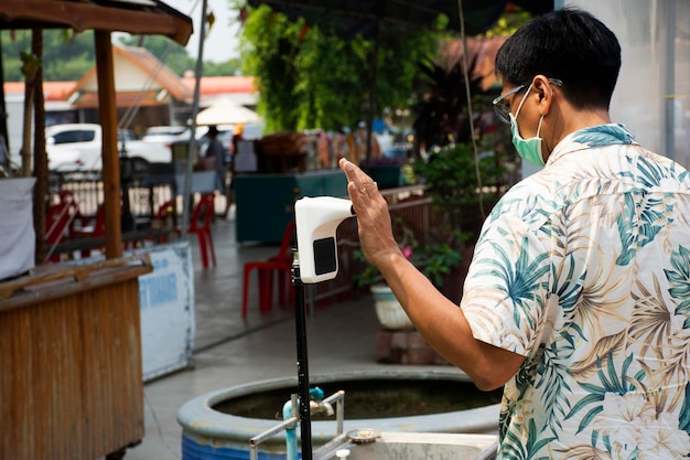 Thaise man-reizigers gebruiken handscan om de lichaamstemperatuur te controleren met een infraroodthermometer voor een reisbezoek aan de Wat Lam Phaya-tempel en de lokale drijvende markt op 9 april 2022 in Nakhon Pathom, Thailand