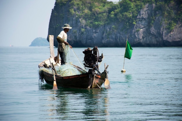 Thaise man vissers mensen zeilen houten lange staart boot visserij drijvend in zee gebruik net vangst visserij marine en vis in de oceaan in mu ko petra national park in pak bara in la ngu stad in satun thailand