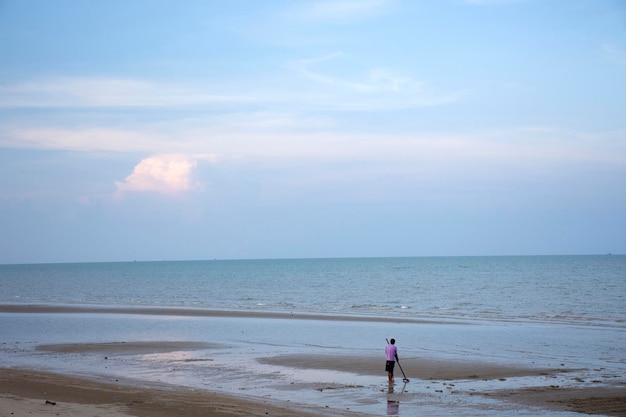 Thaise mannen gebruiken harkgraven om schelpdieren te vinden op Phum Riang Beach in Ao Thai of de Golf van Thailand in het Chaiya-district in Surat Thani, Thailand