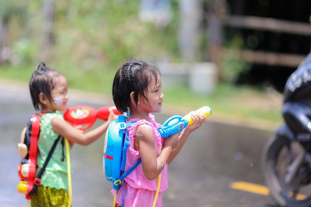 Thaise meisjeskinderen die waterpistolen spelen in songkran-festival met Thaise periodekleding