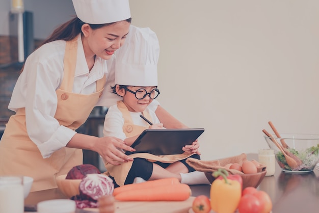 Thaise moeder en kind koken samen thuis. social distancing en blijf thuis blijf veilig. gezinsactiviteit effect van covid-19 en stop uitbraakvirus. opsluiten en thuis in quarantaine.