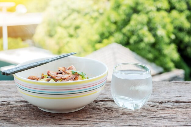 Thaise noedels en drinkwater op de oude houten tafel met prachtige natuur achtergrond.