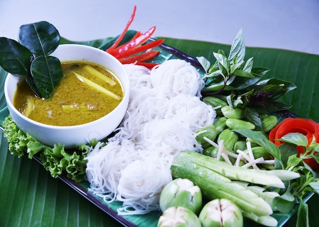 Thaise rijstnoedel die met kruidige kerrie in kom op de achtergrond van het banaanblad wordt gegeten.