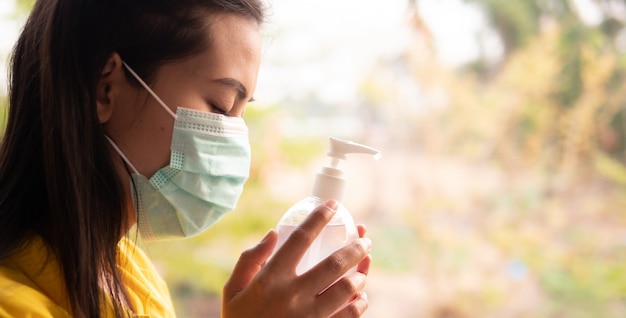 Foto thaise vrouw die een masker draagt met haar hand die een alcoholgel vasthoudt om haar handen te wassen om het virus te voorkomen, covid-19