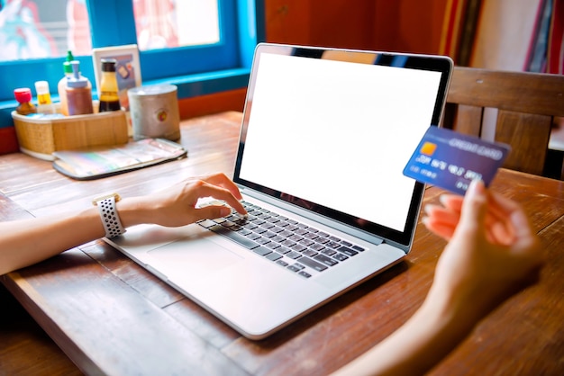 Foto thaise vrouw die sinaasappelsap drinkt in een café met behulp van laptop online winkelen werken met een computer in een coffeeshop