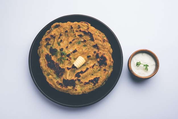 Thalipeeth is een soort hartige meergranenpannenkoek die populair is in Maharashtra, India, geserveerd met wrongel, boter of ghee