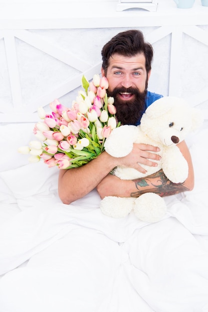 Thank you love valentines day womens day flowers for march 8 good morning surprise happiness about present cheerful bearded man in bed happy birthday gift spring fresh tulip and bear toy