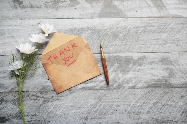 Thank you message and envelope on wooden table