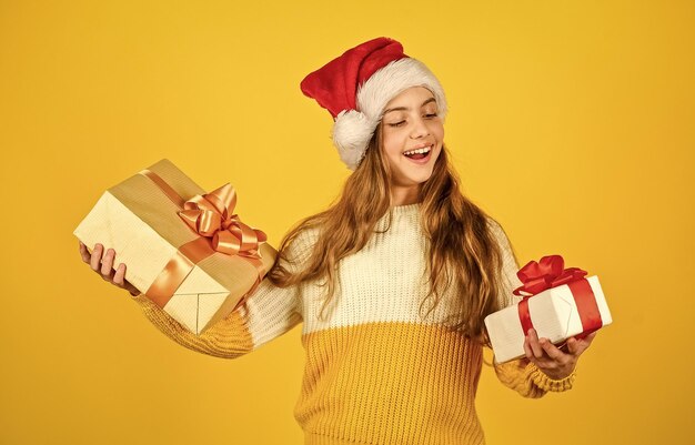 Thank you smiling kid hold purchase presents and gifts from santa claus small girl santa at yellow background xmas party celebration happy new year christmas shopping online time for discount