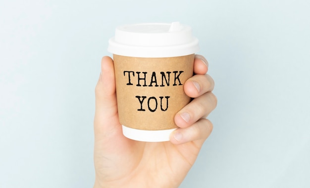 Thank you or thank you concept with a cup of coffee in hands on a light background.