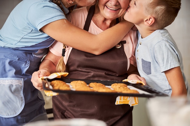 아이들의 사랑을 받는 신선한 쿠키를 들고 감사하는 할머니