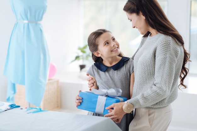 Thanks mom. Cute nice positive girl smiling and looking at her mom while receiving a pleasant surprise from her