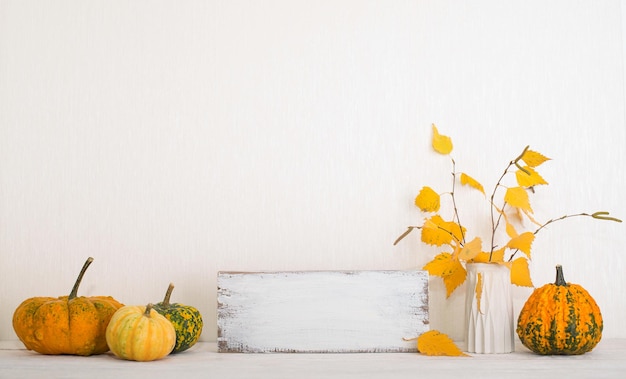 Foto thanksgiving achtergrond mockup met pompoenen en herfstbladeren over witte muur met copyspace