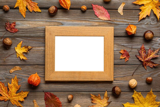 Thanksgiving autumn photo frame with autumn leaves flowers pumpkin on wooden background Flat lay Mock up