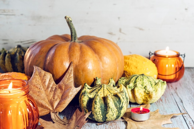 Foto sfondo di ringraziamento, composizione con zucche, foglie secche di autunno, candele su fondo in legno. vacanze autunnali, raccolta della zucca. verdure di stagione.