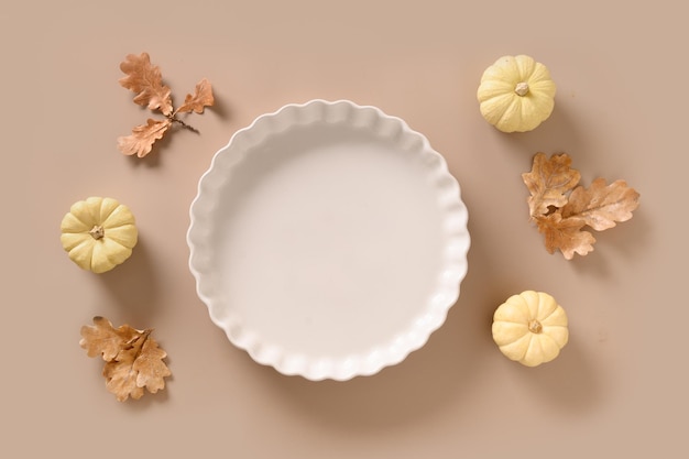 Thanksgiving day background with empty plate for cook american pumpkin pie on beige background view